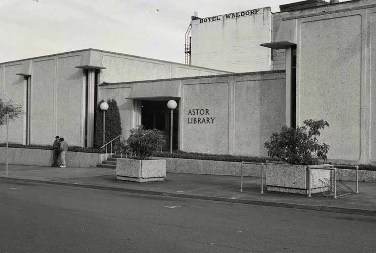 Black and white exterior shot of the entrance to the Astor Library from an empty street.The building is constructed of concrete in a minimal style from the 1960s.